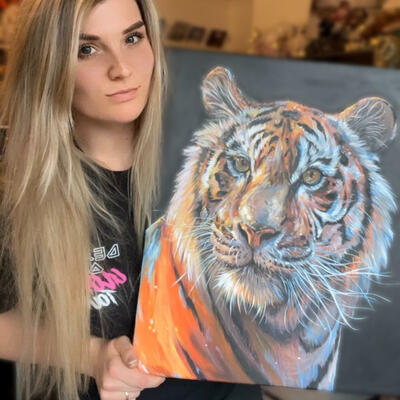 A portrait of a Tiger in acrylic paints held by artist Charlotte Lloyd 