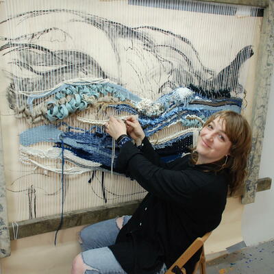 Victoria weaving an ocean landscape in her studio from recycled and natural fibres on a purpose built loom.