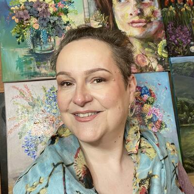 Gabrielle Vickery artist in front of floral paintings and an oil portrait
