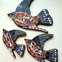 A trio of Swallows in Flight; ceramics on wood.