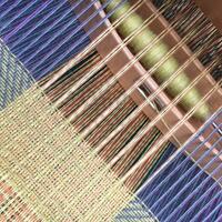 A handwoven scarf being woven on the loom