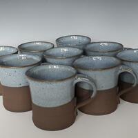 Group of stoneware mugs on dark clay
