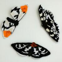 Eclipse Woven Tapestry deatail of 3 woven moths with black and white wing patterns, one also has orange tips to the upper wings 