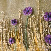 Detail of a woven tapestry with small purple woven flowers embedded into a woven background of yellow grasses on a translucent golden woven fishing line sky