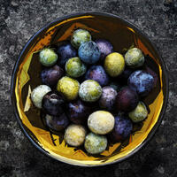 Spanish bowl filled with green, yellow and purple plums collage