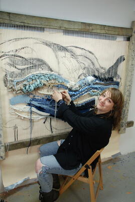 Victoria weaving an ocean landscape in her studio from recycled and natural fibres on a purpose built loom.