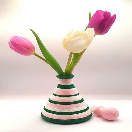 Decorative glass bottle wrapped in green, pink and cream cotton stripes of varying thicknesses.